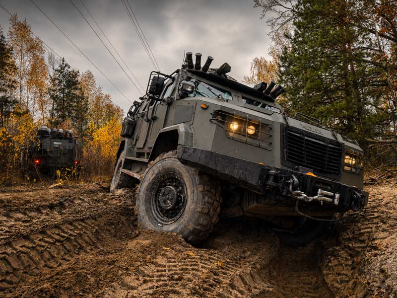 military personal armored vehicle pixel camo on 4 wheels fast driving on a heel. very low angle view 
